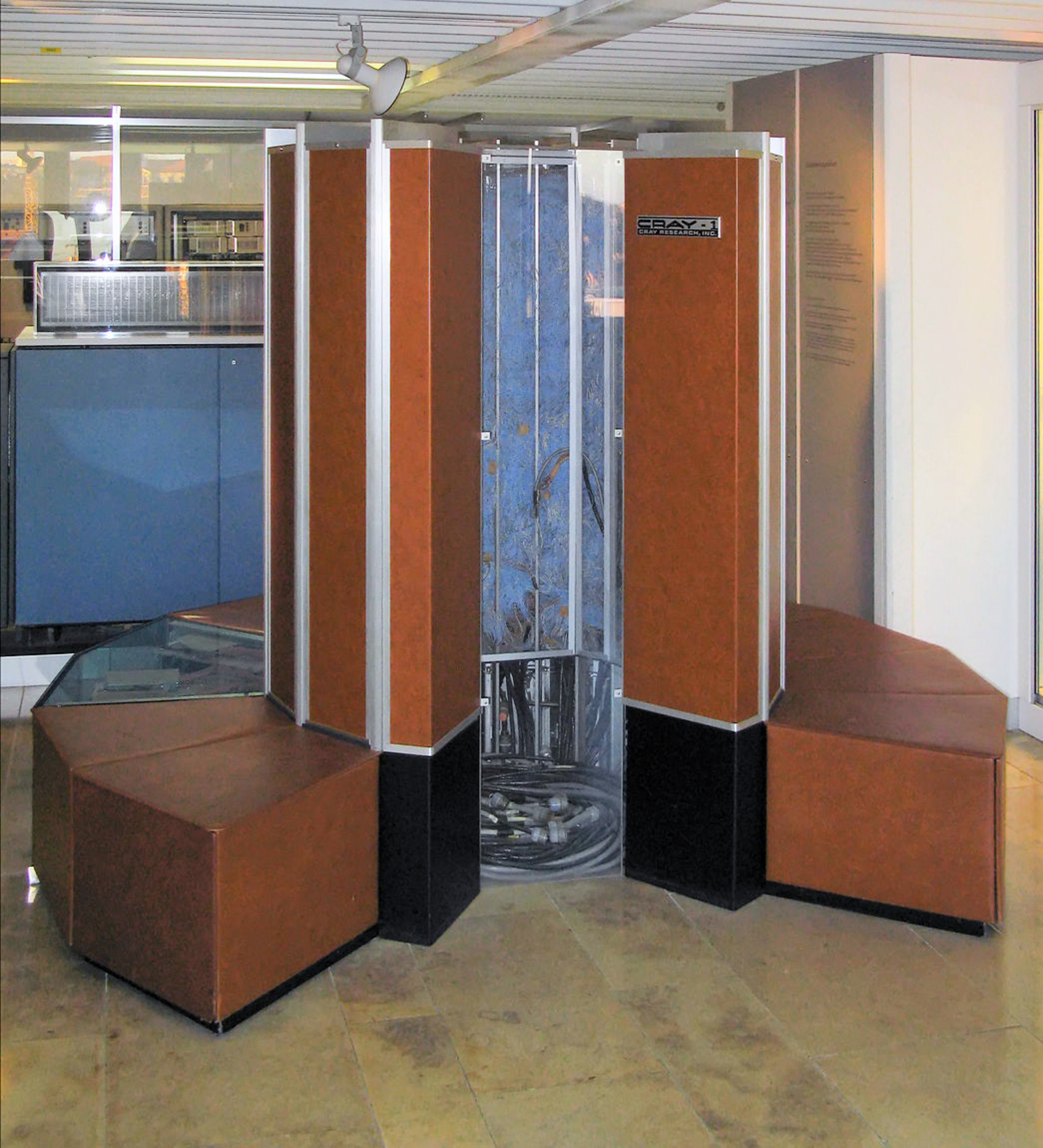 A Cray-1 on display at the Computer History Museum in Mountain View, California. The C-shaped cabinet is structural: every chassis bay is wired to its neighbours through twisted-pair cables that have been individually cut to specific lengths to equalise signal-propagation times. The leather-padded bench around the base hides the power supplies and the Freon cooling system. Photo: Wikimedia Commons, CC BY-SA 4.0.