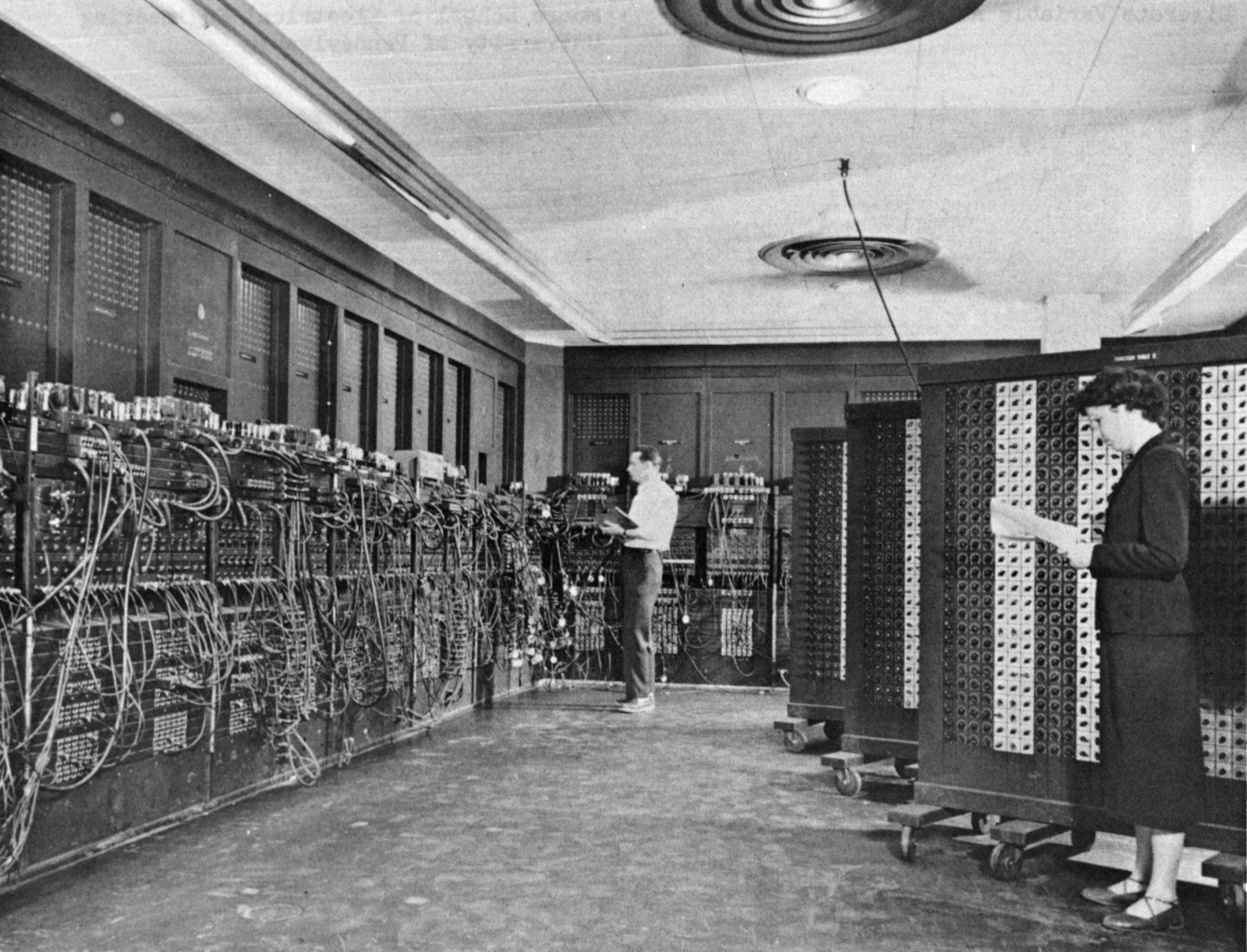 Glen Beck and Betty Snyder program the ENIAC at the Ballistic Research Laboratory, building 328. The long row of panels -- forty in total, arranged in a U-shape -- fills the room. U.S. Army photo, public domain.