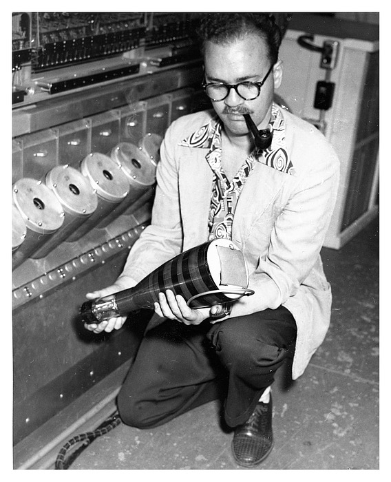 James Pomerene holds a Williams cathode-ray memory tube beside the IAS machine, 1952. When RCA's Selectron tubes failed to arrive on schedule, Pomerene's team adapted commercial oscilloscope tubes into random-access memory. Photo: Alan Richards, Shelby White and Leon Levy Archives Center, IAS, CC BY 4.0.