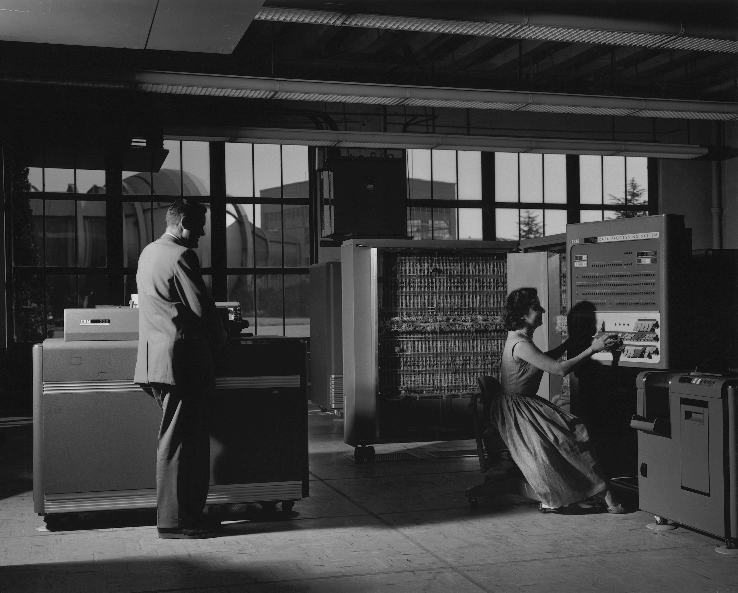 IBM 704 console operators William Mersman and Marcelline Chartz (Marcie Smith) at NASA Ames, October 3, 1958. The three rows of rectangular displays across the top are magnetic drum indicators. Photo: NASA Ames (ARC-1958-A-24321), public domain.