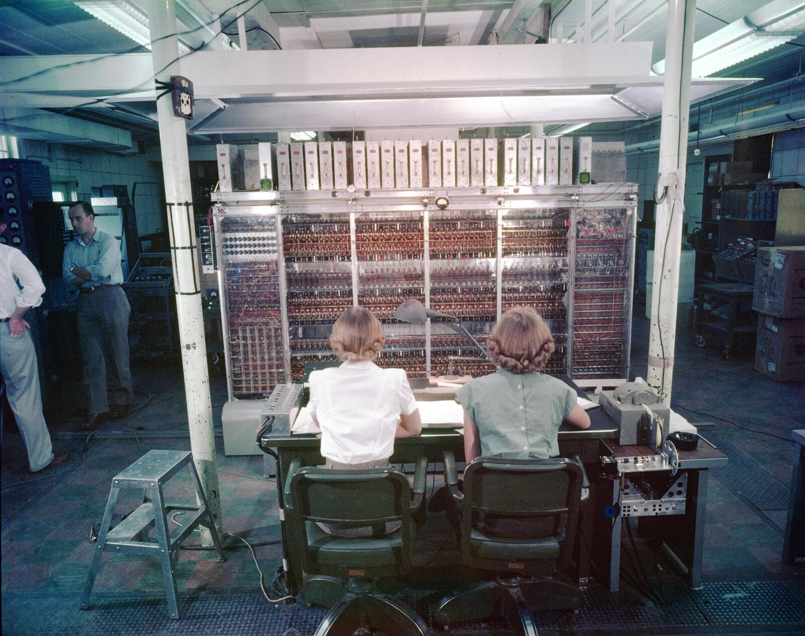 Operators in front of the MANIAC I at Los Alamos, 1952. Note the horseshoe hung on the pillar -- with thousands of vacuum tubes, you needed all the luck you could get. Los Alamos National Laboratory, public domain.